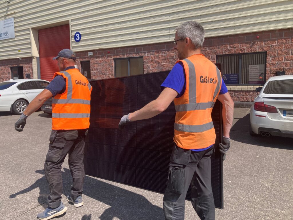 Refer a friend Image of Go Solar installation team carrying solar panel.